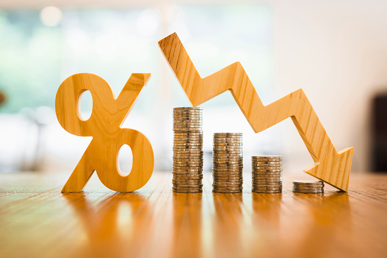 Coins stacked up with percentage sign and reducing arrow